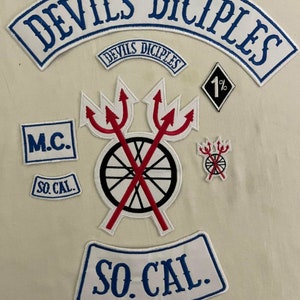 Könnte beinhalten: Eine Sammlung von weißen, blauen und roten gestickten Patches mit den Worten "Devils Disciples", "M.C.", "So. Cal." und "1%". Die Patches zeigen ein Rad mit gekreuzten Dreizacken, einen kleinen Dreizack und eine Diamantform.