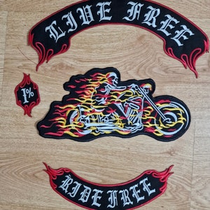 May include: Three embroidered patches with a motorcycle, flames, and the text "Live Free" and "Ride Free". The motorcycle patch features a skeleton riding a motorcycle with flames coming from the wheels. The "Live Free" patch is black with red trim and the "Ride Free" patch is red with black trim.