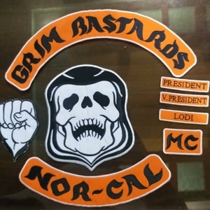 May include: A set of embroidered patches featuring a skull with a hooded head, a fist, and the text "Grim Bastards Nor-Cal MC" in orange and black. The patches also include the text "President", "V.President", and "Lodi".