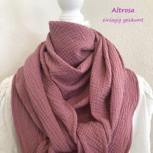 Könnte beinhalten: Ein weicher, rosa, gewaffelter Baumwollschal. Der Schal ist gefaltet und über eine weiße Puppe gelegt. Der Text "Altrrosa einlagig gesäumt" ist in der oberen rechten Ecke des Bildes sichtbar.