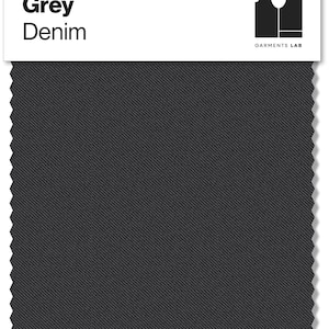 May include: A swatch of grey denim fabric. The fabric has a diagonal weave pattern and is a solid, medium grey color. The words "Grey Denim" are printed in bold, black letters at the top left. The words "GARMENTS LAB" are printed below a black logo at the top right.