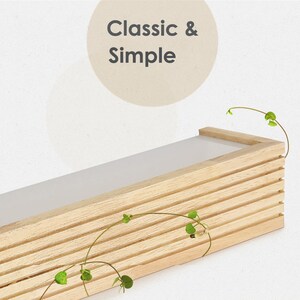 May include: A light wood shelf with a white top and a slatted design. The shelf is empty and has a few green vines hanging from it. The text "Classic & Simple" is written in a circle above the shelf.