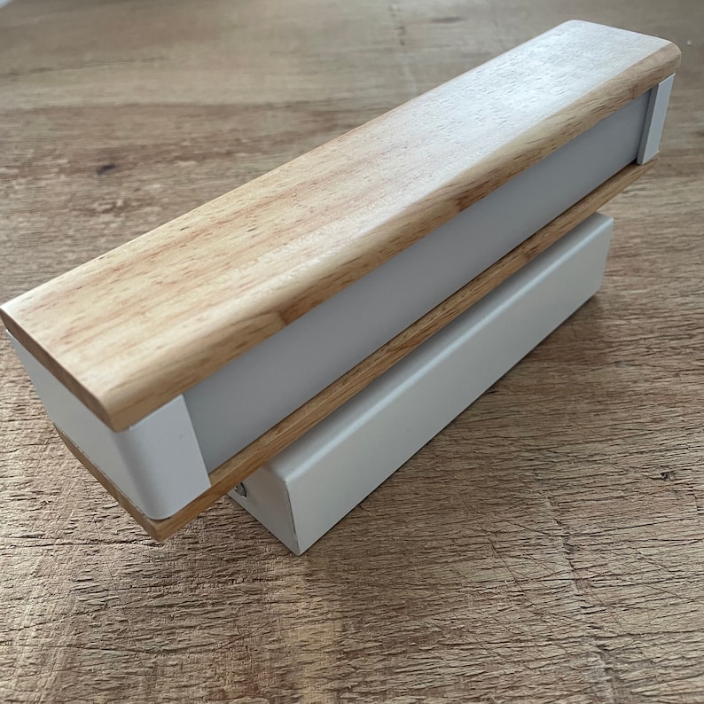 May include: A wooden and white wall light fixture with a rectangular shape. The light fixture has a wooden top and a white base.