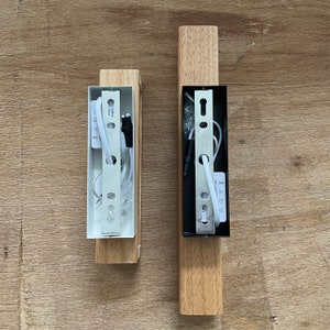 May include: Two wooden wall sconces with white and black electrical wiring and metal mounting plates. The sconces are unfinished and have a natural wood color.