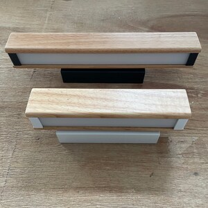 May include: Two wooden wall sconces with white light diffusers. The top sconce has a black base and the bottom sconce has a white base.
