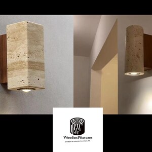 May include: Two wall sconces. One is rectangular, the other cylindrical, both with a light beige stone finish and a warm light. They are mounted on a dark wood backing. The sconces are designed for indoor use.