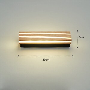 May include: A modern wall light fixture with a wooden frame and integrated LED lights. The light is 30 inches wide and 8 inches tall.