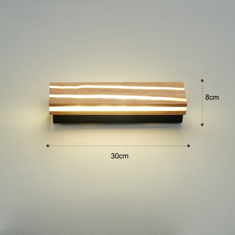May include: A modern wall light fixture with a wooden frame and integrated LED lights. The light is 30 inches wide and 8 inches tall.