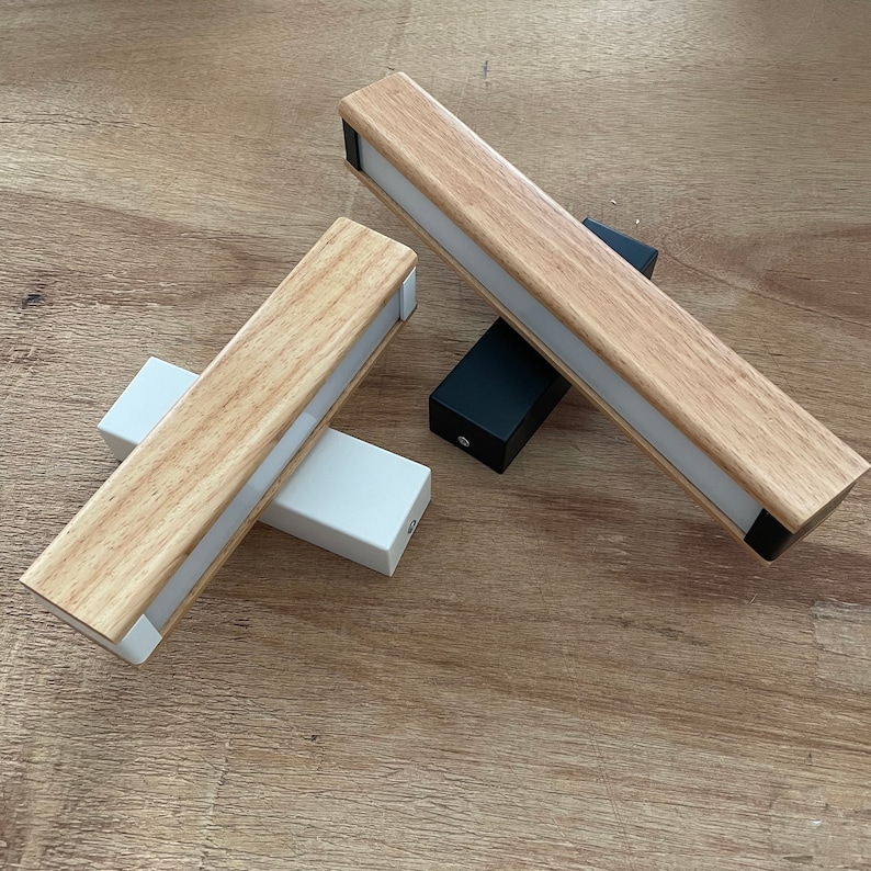 May include: Two wooden light fixtures with white diffusers. One fixture is laying on a wooden surface, while the other is standing upright with a black base.