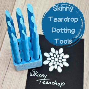 May include: A set of eight blue teardrop-shaped dotting tools in a blue plastic holder. The tools are used for nail art and other crafts. The tools are labeled "Skinny Teardrop Dotting Tools".