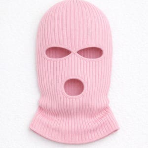 Puede incluir: Un pasamonta&ntilde;as de punto rosa claro con tres aberturas para ojos y boca. La prenda para la cabeza est&aacute; hecha de tejido de punto acanalado. El pasamonta&ntilde;as est&aacute; dise&ntilde;ado para cubrir la cabeza y el cuello.