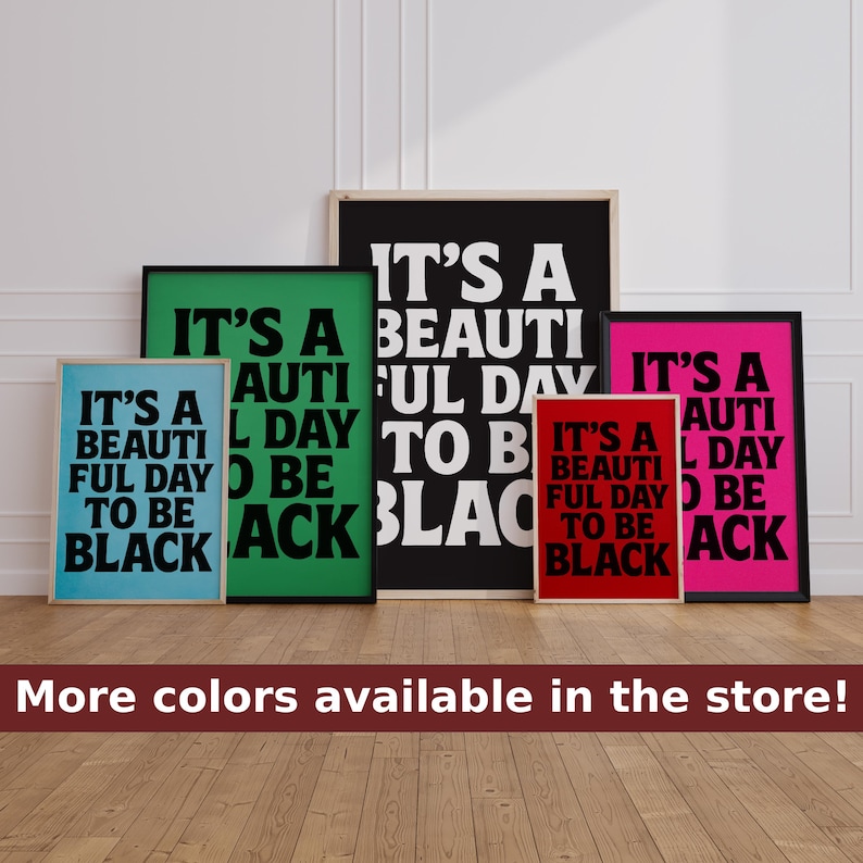 May include: A collection of framed art prints with the text "IT'S A BEAUTIFUL DAY TO BE BLACK" in bold white letters on various colored backgrounds, including black, green, pink, red, and blue. The prints are displayed on a wooden floor.