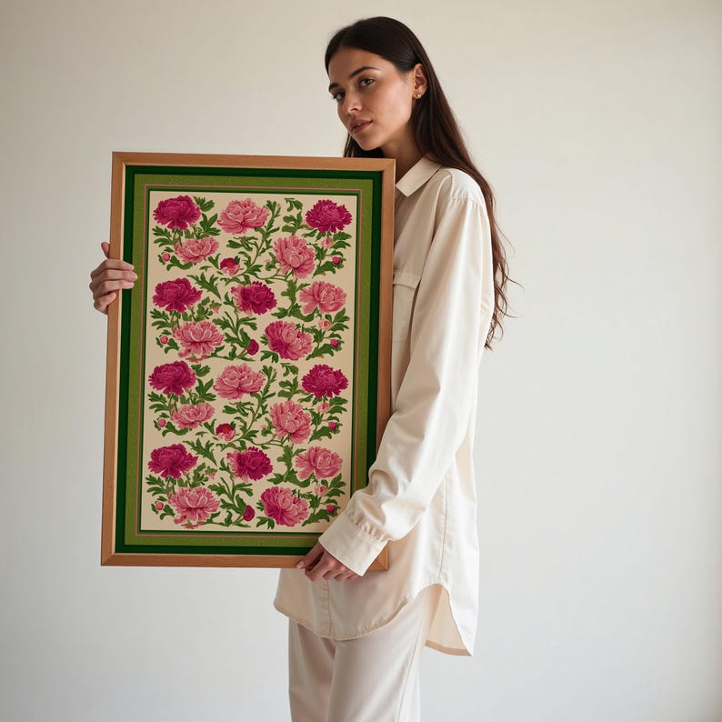 Puede incluir: Una impresi&oacute;n floral enmarcada con un patr&oacute;n repetido de peon&iacute;as rosas y fucsias y hojas verdes sobre un fondo crema. El marco es marr&oacute;n claro con un borde verde. La obra de arte est&aacute; sostenida por una persona.