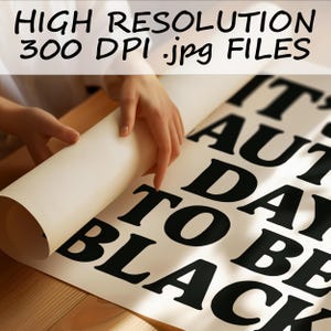 May include: A person is unrolling a large white poster with black text that reads "IT'S AUTUMN DAY TO BE BLACK." The top of the poster has the text "HIGH RESOLUTION 300 DPI .jpg FILES."
