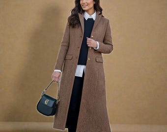 May include: A long brown herringbone coat with a notched collar and button closure. The coat is worn over a white collared shirt and a black sweater. A black handbag with a gold clasp is held in the hand.