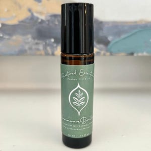 May include: A brown glass essential oil roller bottle with a black cap. The label is green with white text and a leaf design. The text on the label reads "Restored Essentials" and "Brainwave Brilliance". The bottle contains 10 ml / .33 fl oz.