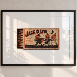 May include: A framed print featuring a vintage-style matchbox labeled JACK O LITE. The box illustration shows three pumpkin-headed figures in costumes, with text reading SAFETY MATCHES FOR LIGHTING PUMPKINS, MADE IN U.S.A., and AVERAGE CONTENTS 50.