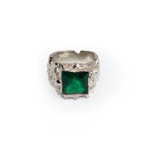 May include: A silver ring with a textured band and a square green gemstone.