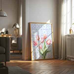 Digital wall art featuring a watercolor pink tulip bouquet on a blue and white Delftware tile background. This botanical poster is ideal for cottagecore, farmhouse, and Mediterranean-style kitchen or bathroom decor. With a background resembling Portuguese azulejo tiles and vibrant spring flowers, it offers a fresh and airy look. This printable image is perfect as a Mother's Day gift or seasonal spring decor.