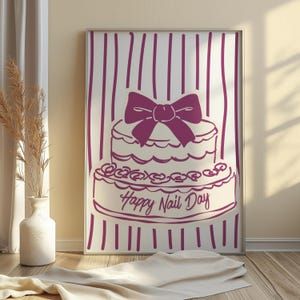 以下が含まれることがあります： 大きなリボンが付いた2段ケーキのデザインが特徴の額入りプリント。ケーキは濃い紫で縁取られ、下部には「Happy Nail Day」の文字が書かれています。背景には紫色の縦縞模様があります。