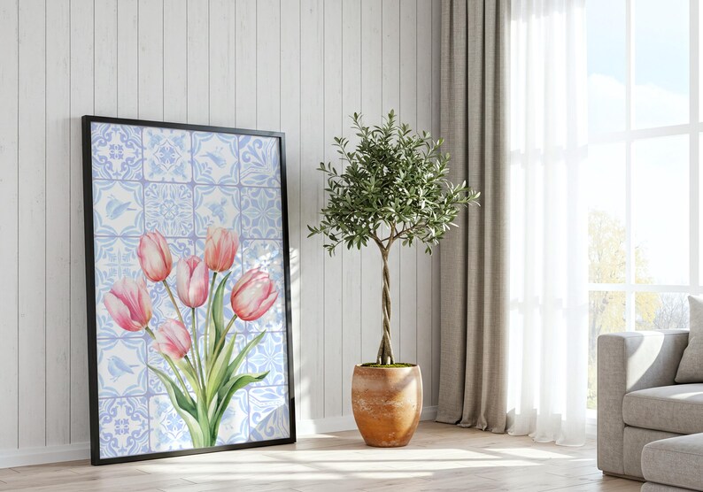 Digital wall art featuring a watercolor pink tulip bouquet on a blue and white Delftware tile background. This botanical poster is ideal for cottagecore, farmhouse, and Mediterranean-style kitchen or bathroom decor. With a background resembling Portuguese azulejo tiles and vibrant spring flowers, it offers a fresh and airy look. This printable image is perfect as a Mother's Day gift or seasonal spring decor.