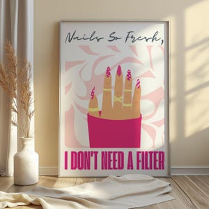 May include: A framed poster with the text "Nails So Fresh, I DON'T NEED A FILTER." The artwork features a hand with long, painted nails in pink and gold, adorned with gold rings. The background has a pink and white swirl design.