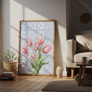 Digital wall art featuring a watercolor pink tulip bouquet on a blue and white Delftware tile background. This botanical poster is ideal for cottagecore, farmhouse, and Mediterranean-style kitchen or bathroom decor. With a background resembling Portuguese azulejo tiles and vibrant spring flowers, it offers a fresh and airy look. This printable image is perfect as a Mother's Day gift or seasonal spring decor.