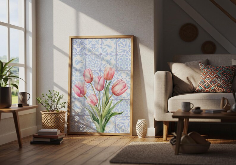 Digital wall art featuring a watercolor pink tulip bouquet on a blue and white Delftware tile background. This botanical poster is ideal for cottagecore, farmhouse, and Mediterranean-style kitchen or bathroom decor. With a background resembling Portuguese azulejo tiles and vibrant spring flowers, it offers a fresh and airy look. This printable image is perfect as a Mother's Day gift or seasonal spring decor.