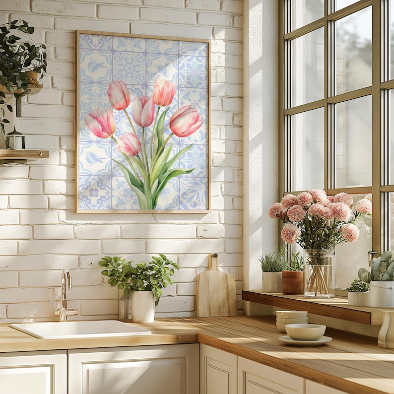 Digital wall art featuring a watercolor pink tulip bouquet on a blue and white Delftware tile background. This botanical poster is ideal for cottagecore, farmhouse, and Mediterranean-style kitchen or bathroom decor. With a background resembling Portuguese azulejo tiles and vibrant spring flowers, it offers a fresh and airy look. This printable image is perfect as a Mother's Day gift or seasonal spring decor.