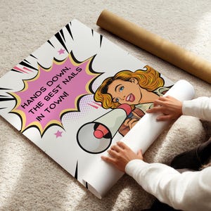 High-quality paper poster being unrolled on a carpet to show the full design. Comic book explosion background with a bold marketing slogan for nail artists. Durable wall art print for high-traffic salon areas.