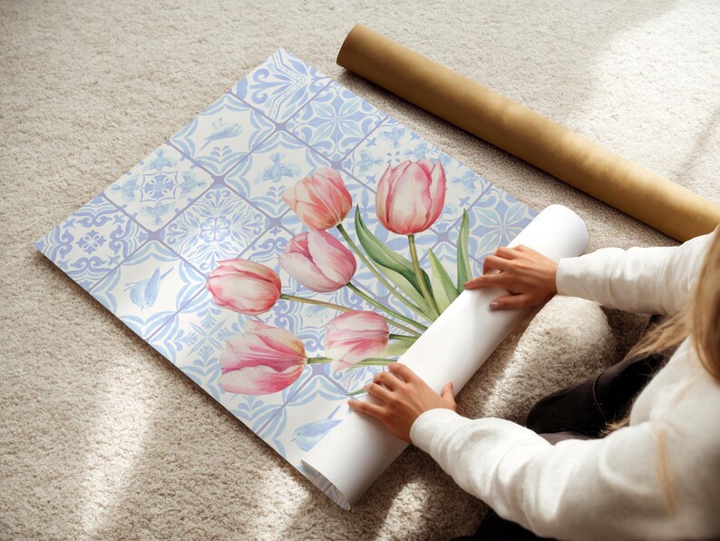 Digital wall art featuring a watercolor pink tulip bouquet on a blue and white Delftware tile background. This botanical poster is ideal for cottagecore, farmhouse, and Mediterranean-style kitchen or bathroom decor. With a background resembling Portuguese azulejo tiles and vibrant spring flowers, it offers a fresh and airy look. This printable image is perfect as a Mother's Day gift or seasonal spring decor.