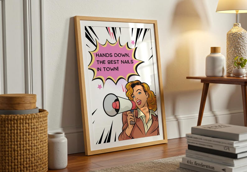 Large framed nail salon sign leaning against a wall on wooden flooring. Vintage pop art design with a funny "Best Nails in Town" quote. Eye-catching decor for a manicurist's studio or pedicure station to attract clients.