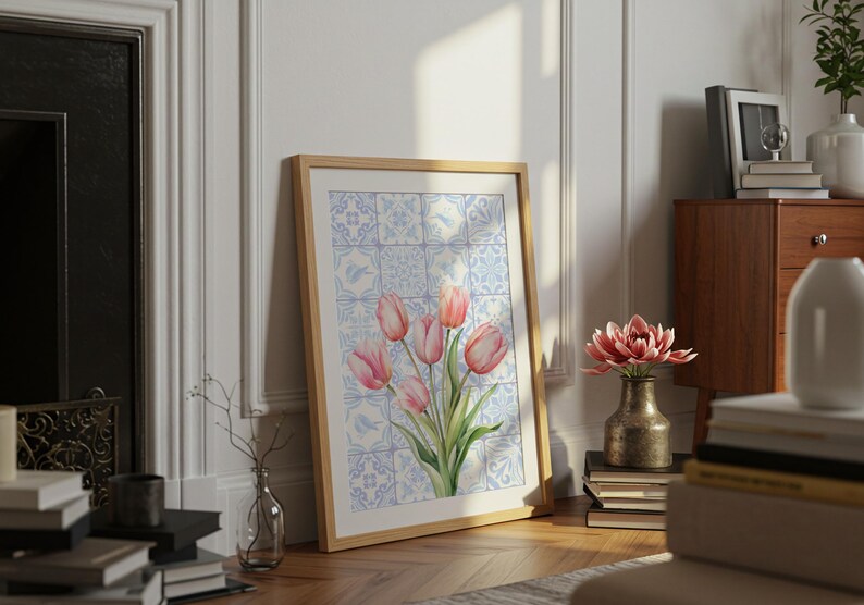 Digital wall art featuring a watercolor pink tulip bouquet on a blue and white Delftware tile background. This botanical poster is ideal for cottagecore, farmhouse, and Mediterranean-style kitchen or bathroom decor. With a background resembling Portuguese azulejo tiles and vibrant spring flowers, it offers a fresh and airy look. This printable image is perfect as a Mother's Day gift or seasonal spring decor.