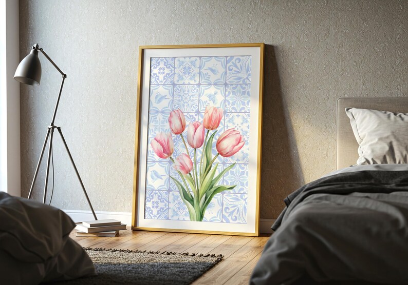 Digital wall art featuring a watercolor pink tulip bouquet on a blue and white Delftware tile background. This botanical poster is ideal for cottagecore, farmhouse, and Mediterranean-style kitchen or bathroom decor. With a background resembling Portuguese azulejo tiles and vibrant spring flowers, it offers a fresh and airy look. This printable image is perfect as a Mother's Day gift or seasonal spring decor.