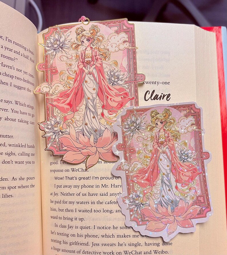 May include: Two decorative bookmarks and a sticker featuring a pink-robed anime character with blonde hair, set against a floral and cloud background. The text "twenty-one Claire" is visible on the book page. The design includes lotus flowers and a decorative border.