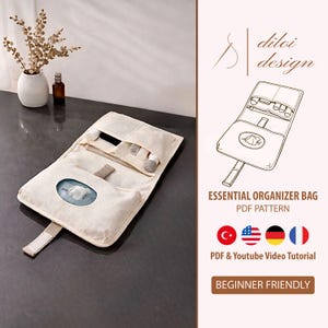 Pode incluir: Bolsa organizadora essencial bege, aberta para exibir o conteúdo, com um pequeno compartimento para lenços. A bolsa está sobre uma superfície escura. O texto "ESSENTIAL ORGANIZER BAG PDF PATTERN" é visível. O design é adequado para iniciantes.