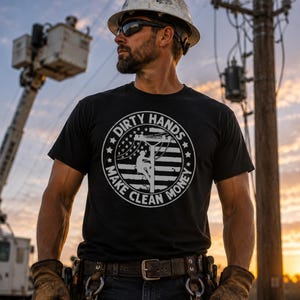 May include: A black short-sleeved t-shirt featuring a white circular graphic with the text "DIRTY HANDS MAKE CLEAN MONEY" surrounding an illustration of a utility worker on a pole against a stylized American flag background.