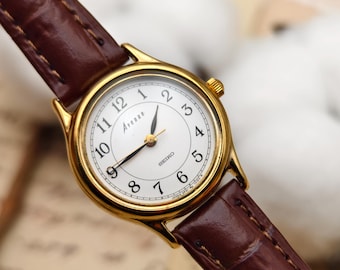 Orologio da donna vintage Seiko Avenue al quarzo color oro con quadrante bianco e cinturino in pelle marrone.