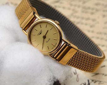 Reloj Longines vintage para mujer, tono dorado, cuarzo, pulsera de malla elástica, esfera minimalista.