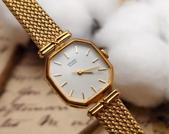 Reloj de cuarzo vintage Seiko para mujer, tono dorado, caja octogonal, brazalete de malla y esfera blanca.