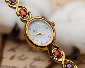 Orologio da donna Bulova vintage anni '90 al quarzo color oro con cassa ovale e bracciale con gemme multicolore.