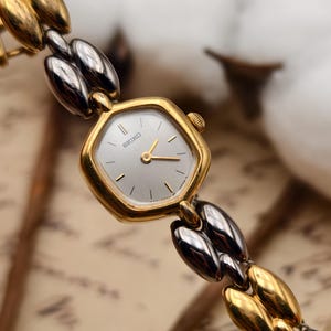 Reloj Seiko vintage de los años 90 para mujer, de cuarzo, con brazalete bicolor dorado y caja cuadrada.