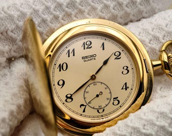 Reloj de bolsillo Seiko de cuarzo vintage, tono dorado, caja tipo cazador completa, números arábigos, clásico.