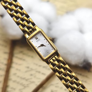 Reloj de pulsera rectangular de cuarzo Seiko para mujer, tono dorado, años 80, esfera plateada.