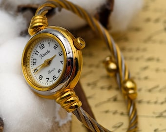Reloj de cuarzo vintage Xanadu para mujer de los años 90 con brazalete de cable trenzado en tono dorado.