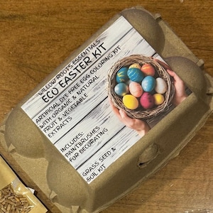 May include: A brown cardboard egg carton with a label that reads "Willow Roots Essentials Eco Easter Kit". The label also includes the text "Artificial Dye Free Egg Coloring Kit with Organic & Natural Fruit & Vegetable Extracts". The label has a picture of a nest with colorful Easter eggs.