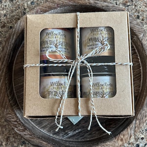 Puede incluir: Un juego de regalo de cuatro pequeños frascos de productos Willow Roots Essentials, empaquetados en una caja de cartón marrón atada con hilo. Los frascos contienen productos con aroma a Pumpkin Spice Buttercream, Caramel Popcorn, Spiced Apple Cider y Vanilla Pumpkin Marshmallow.