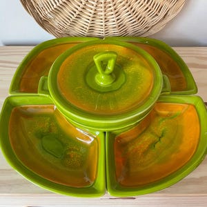 May include: A green and orange ceramic serving dish with four sections. The center section is a bowl with a lid. The dish is perfect for serving snacks or appetizers.