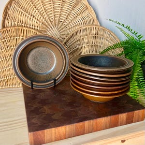 May include: A set of three ceramic mugs with a speckled, matte finish. The mugs are in shades of cream, light gray, and dark gray. Each mug has a simple, minimalist design, perfect for coffee or tea.