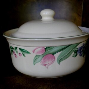 May include: A white ceramic serving bowl with a matching lid. The bowl is decorated with pink tulips, green leaves, and small red berries. The rim has a thin green border. A classic piece for serving.